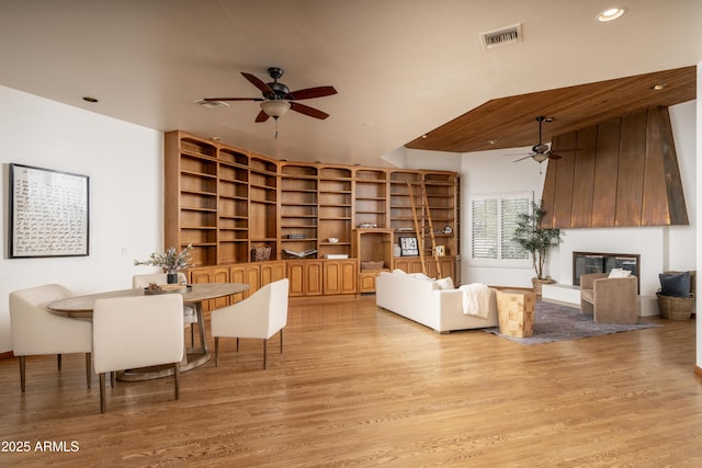 dining room featuring light wood-type flooring, visible vents, recessed lighting, a large fireplace, and ceiling fan