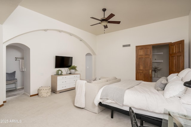 bedroom featuring a ceiling fan, baseboards, visible vents, arched walkways, and light carpet