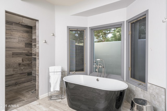 bathroom featuring tiled shower and a freestanding tub