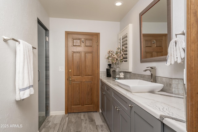 full bathroom with a stall shower, wood finished floors, and vanity