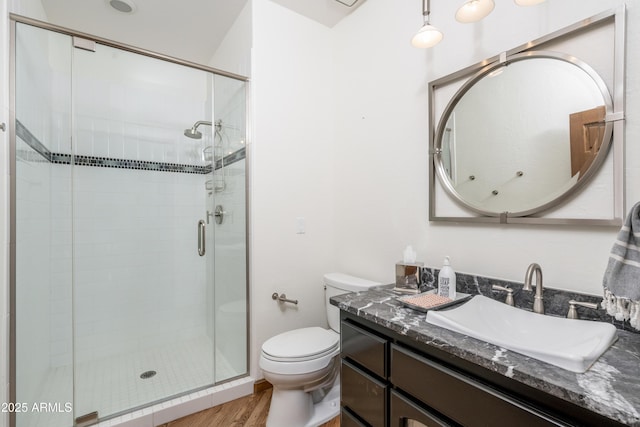 bathroom featuring a shower stall, toilet, vanity, and wood finished floors