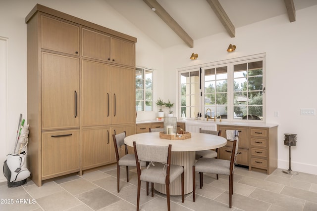 dining space featuring vaulted ceiling with beams and baseboards