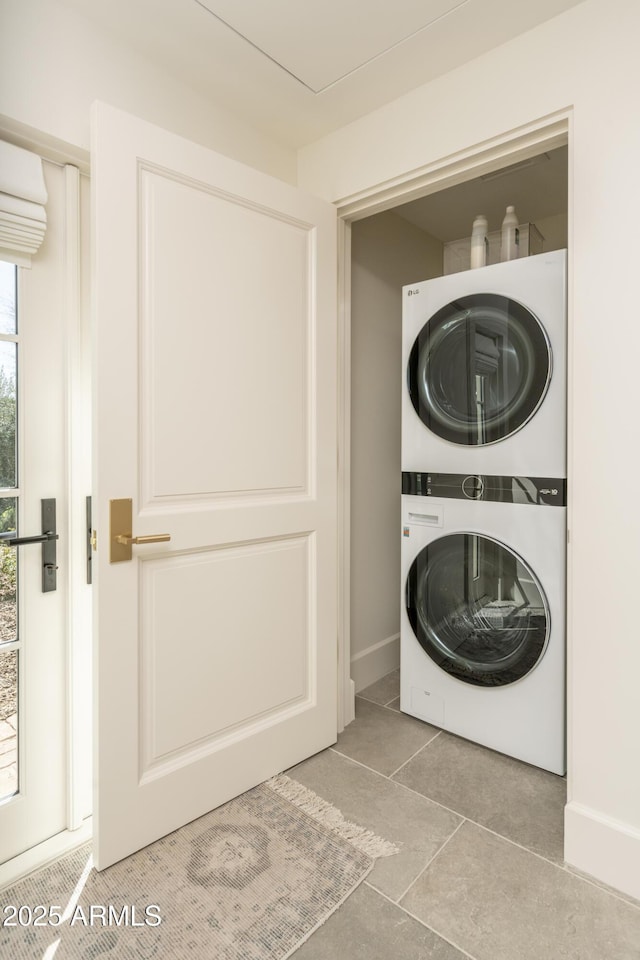 clothes washing area featuring stacked washer and dryer, light tile patterned flooring, and laundry area