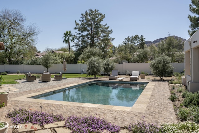 view of swimming pool with a fenced backyard, a mountain view, a diving board, a fenced in pool, and a patio area