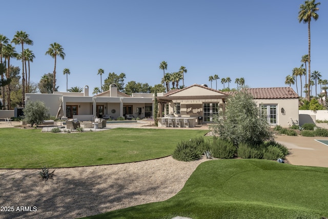 back of property with stucco siding, a patio, and a yard