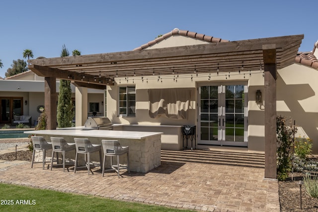 view of patio / terrace featuring grilling area, an outdoor kitchen, french doors, and outdoor wet bar