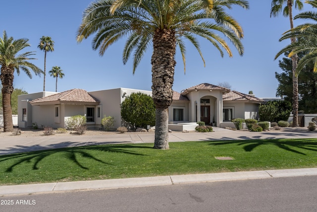 mediterranean / spanish home with a front yard, a tiled roof, and stucco siding