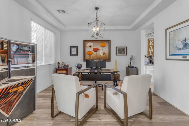 dining space featuring light hardwood / wood-style floors, a chandelier, and a raised ceiling