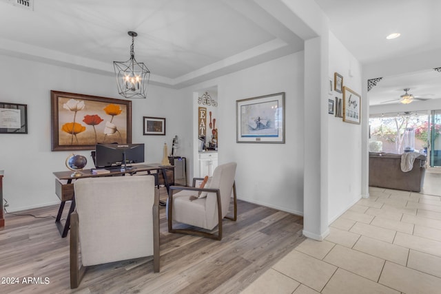 tiled dining room featuring ceiling fan with notable chandelier and a tray ceiling