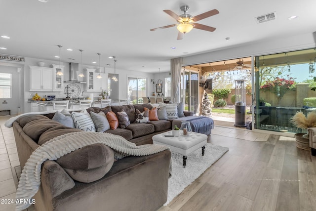 living room featuring a healthy amount of sunlight, light hardwood / wood-style floors, and ceiling fan