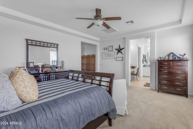 bedroom with ceiling fan, light carpet, and ensuite bathroom