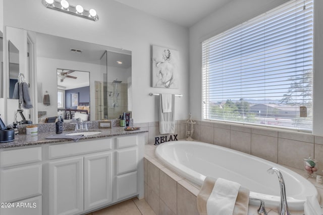 bathroom featuring plenty of natural light, ceiling fan, tiled tub, and vanity