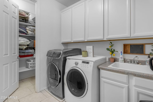 clothes washing area with sink, light tile flooring, cabinets, and separate washer and dryer