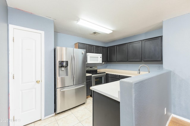 kitchen with light tile patterned floors, appliances with stainless steel finishes, and sink