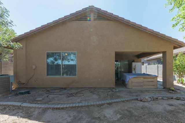 view of home's exterior featuring cooling unit, a hot tub, and a patio