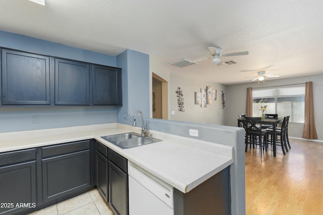 kitchen featuring kitchen peninsula, dishwasher, a textured ceiling, light hardwood / wood-style flooring, and sink