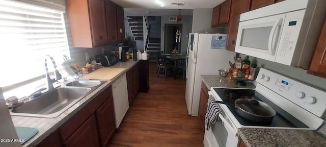 kitchen featuring light countertops, visible vents, brown cabinetry, a sink, and white appliances