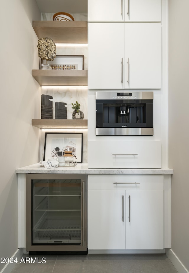 bar featuring beverage cooler, baseboards, and oven