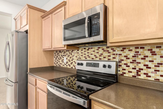 kitchen featuring dark countertops, light brown cabinets, tasteful backsplash, and appliances with stainless steel finishes