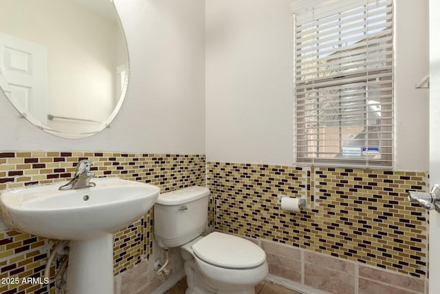 half bathroom featuring a wainscoted wall, toilet, and tile walls