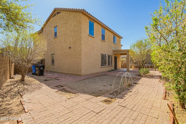 rear view of house with a patio, a fenced backyard, a tile roof, and stucco siding