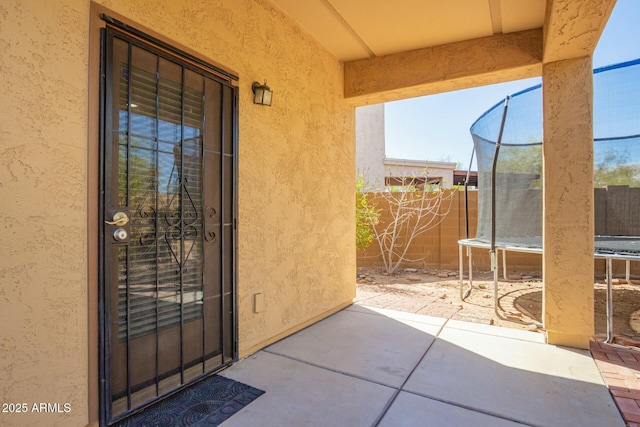 entrance to property featuring stucco siding, a patio, and fence