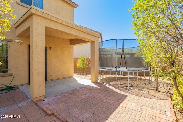 view of patio featuring a trampoline and fence