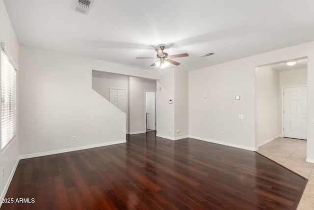 spare room with baseboards, wood finished floors, visible vents, and ceiling fan