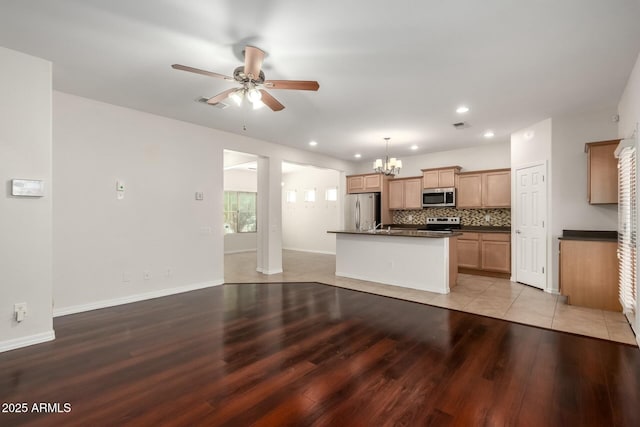 kitchen with light wood-type flooring, visible vents, dark countertops, backsplash, and stainless steel appliances