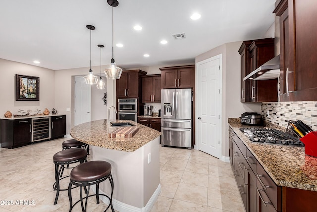 kitchen featuring stainless steel appliances, beverage cooler, a center island with sink, and stone countertops