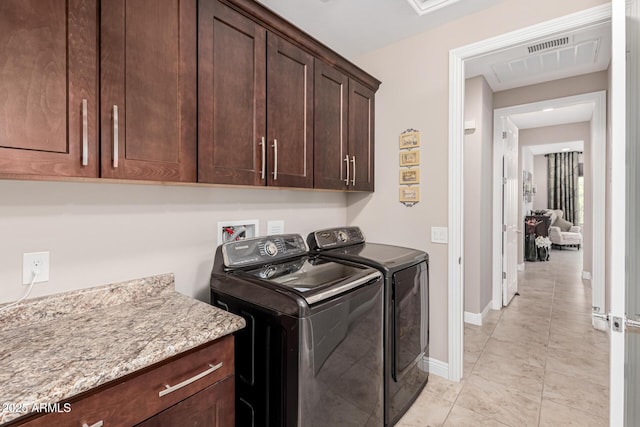 laundry room featuring cabinets, light tile patterned floors, and washer and dryer