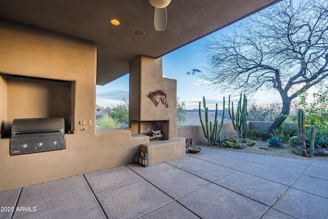 view of patio with a large fireplace, exterior kitchen, and a grill