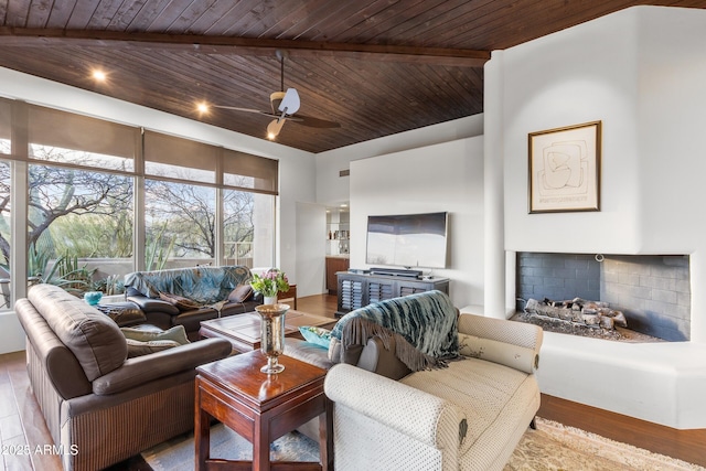 living room featuring a fireplace with raised hearth, ceiling fan, wooden ceiling, and wood finished floors