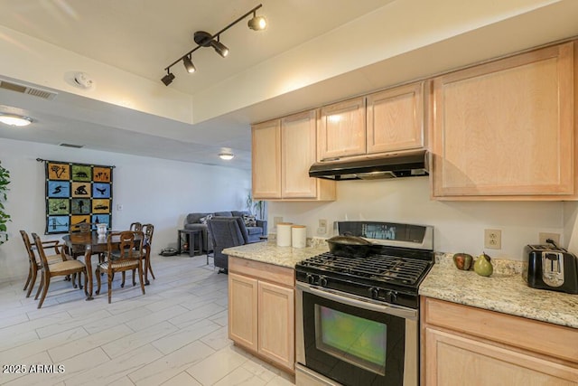 kitchen with under cabinet range hood, stainless steel gas range, and light brown cabinetry