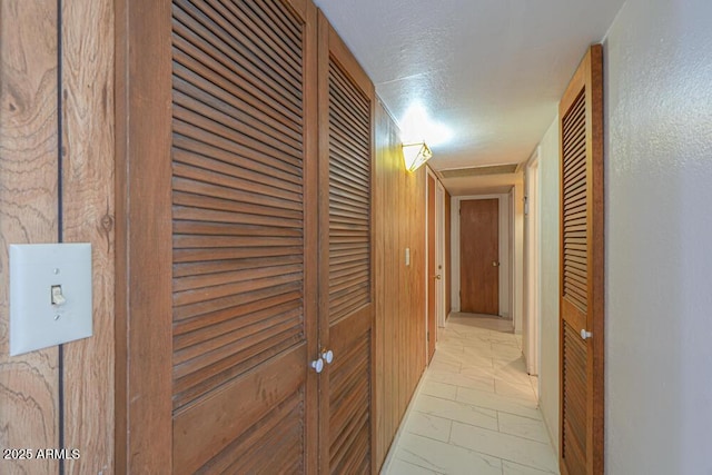 hallway with marble finish floor and a textured ceiling