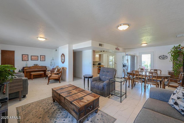 living area with visible vents, marble finish floor, and a textured ceiling