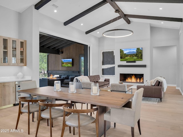 2653 S Pinyon Jay Dr Unit 10, Flagstaff, AZ 86005 - dining space with beamed ceiling, light wood-style flooring, a warm lit fireplace, high vaulted ceiling, and baseboards