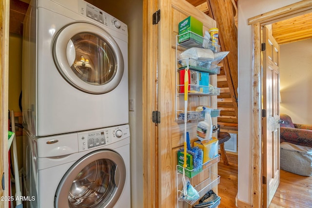 clothes washing area with hardwood / wood-style flooring and stacked washer / drying machine