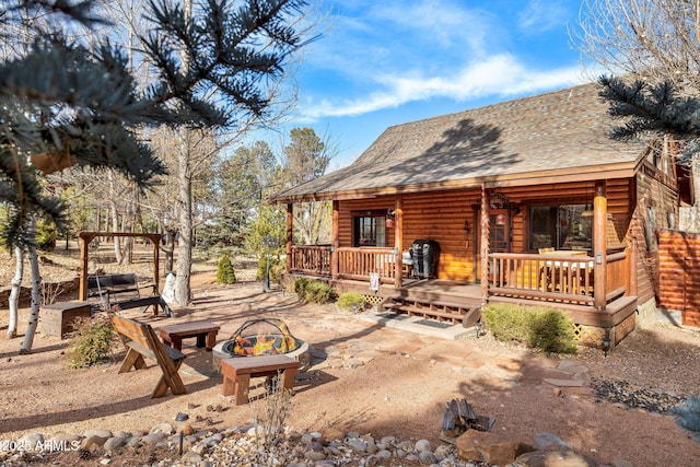 rear view of house featuring a fire pit and a porch