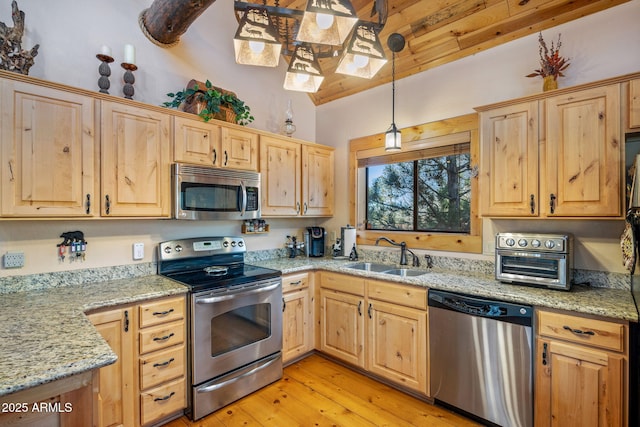 kitchen with pendant lighting, sink, light wood-type flooring, appliances with stainless steel finishes, and light stone counters