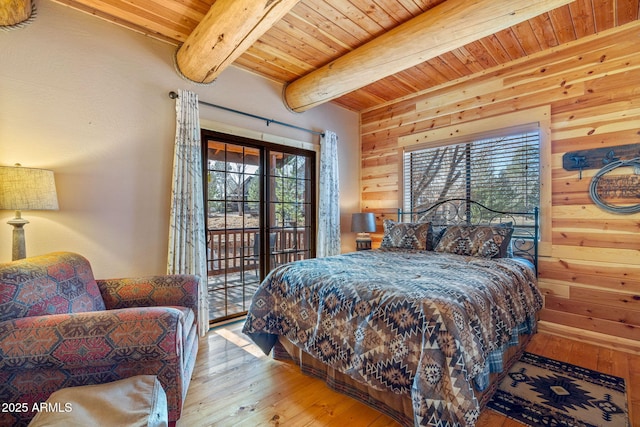 bedroom with wood walls, wood-type flooring, beam ceiling, and multiple windows