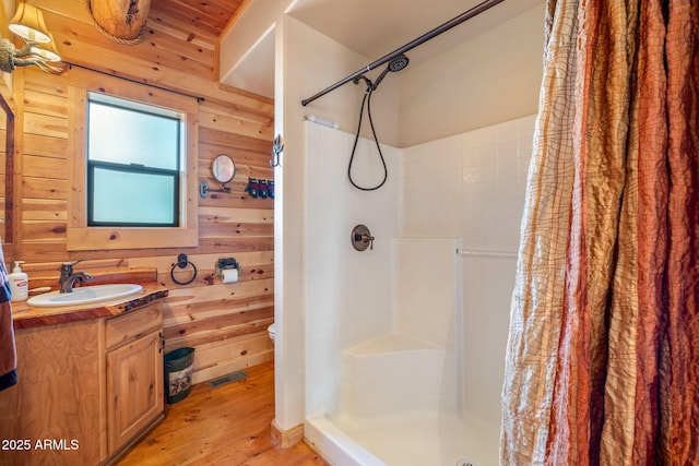 bathroom featuring a shower with shower curtain, vanity, wood walls, and hardwood / wood-style floors