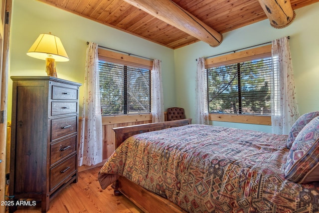 bedroom with beam ceiling, multiple windows, light hardwood / wood-style flooring, and wooden ceiling