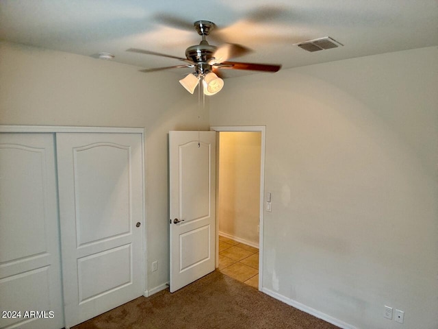 unfurnished bedroom featuring light carpet, a closet, and ceiling fan