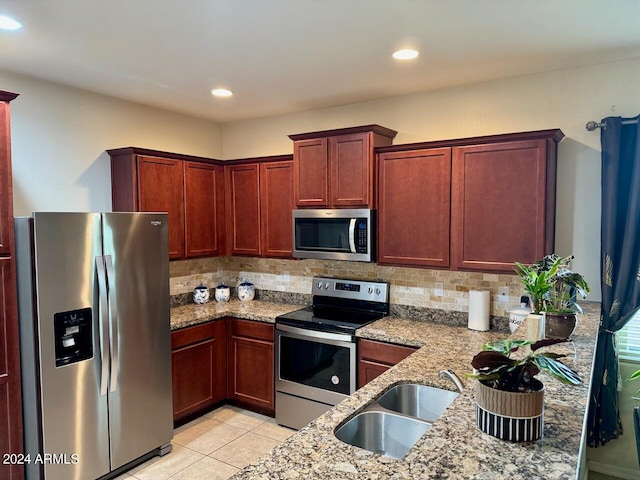 kitchen featuring light stone counters, sink, stainless steel appliances, backsplash, and light tile patterned floors