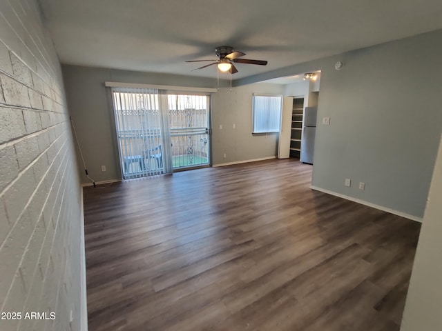 spare room with dark wood finished floors, baseboards, and ceiling fan