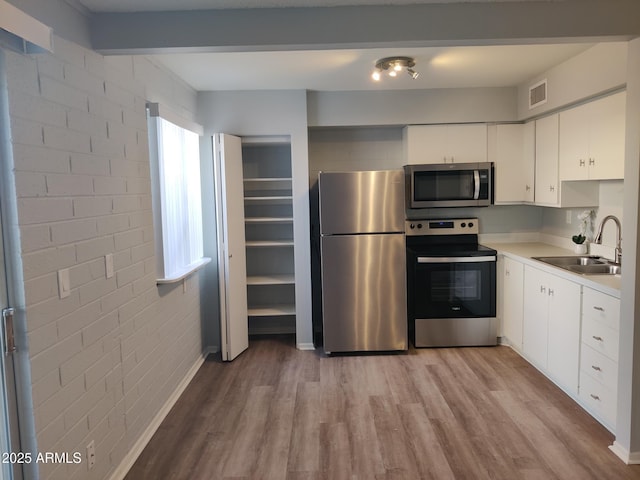 kitchen featuring visible vents, light countertops, light wood-type flooring, appliances with stainless steel finishes, and a sink