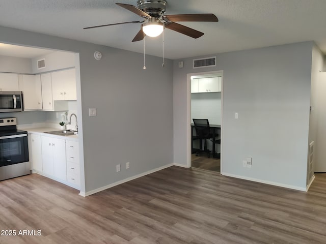 kitchen with a sink, wood finished floors, visible vents, and stainless steel appliances