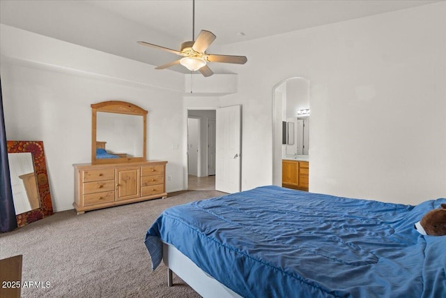 bedroom with arched walkways, a ceiling fan, ensuite bathroom, and carpet