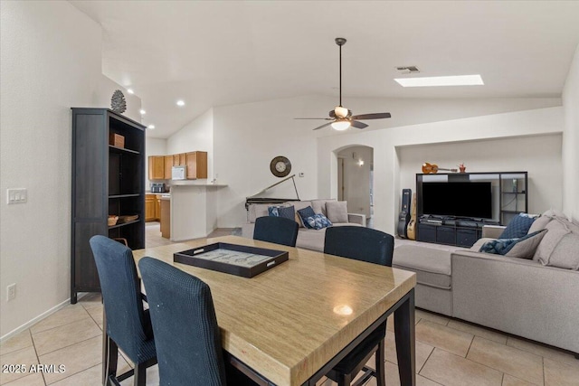 dining room featuring visible vents, lofted ceiling, light tile patterned floors, arched walkways, and a ceiling fan